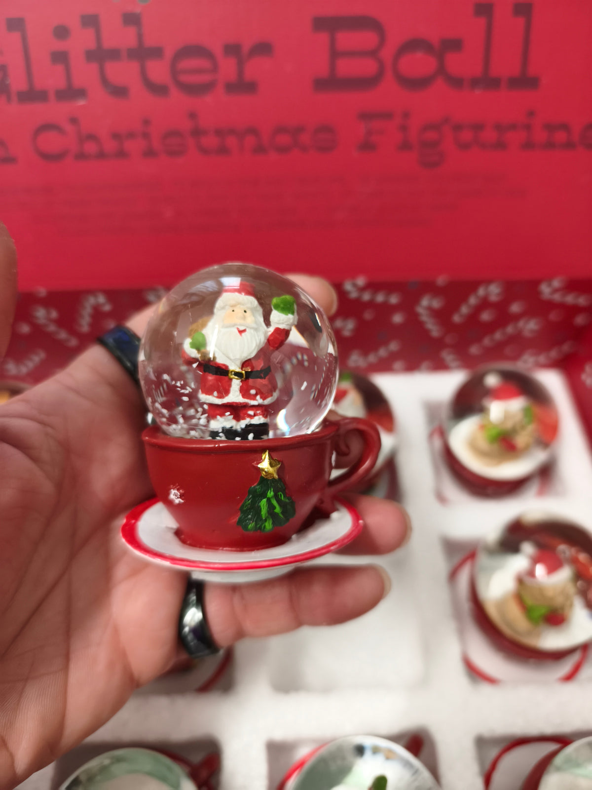 Une Boule à neige en polyrésine avec figurine de Noël sur tasse à café rouge